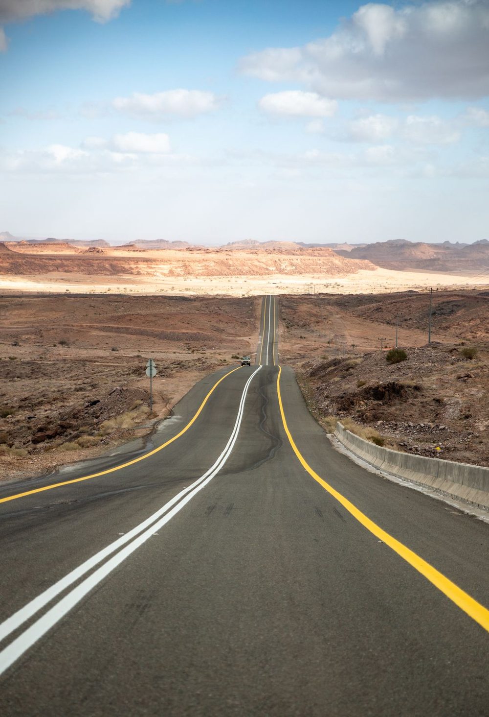 A single car stopped on a remote desert highway